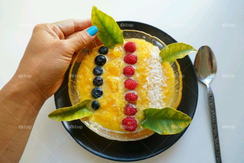 Fresh fruit smoothie - orange smoothie topped blueberries,  raspberries and diced coconut