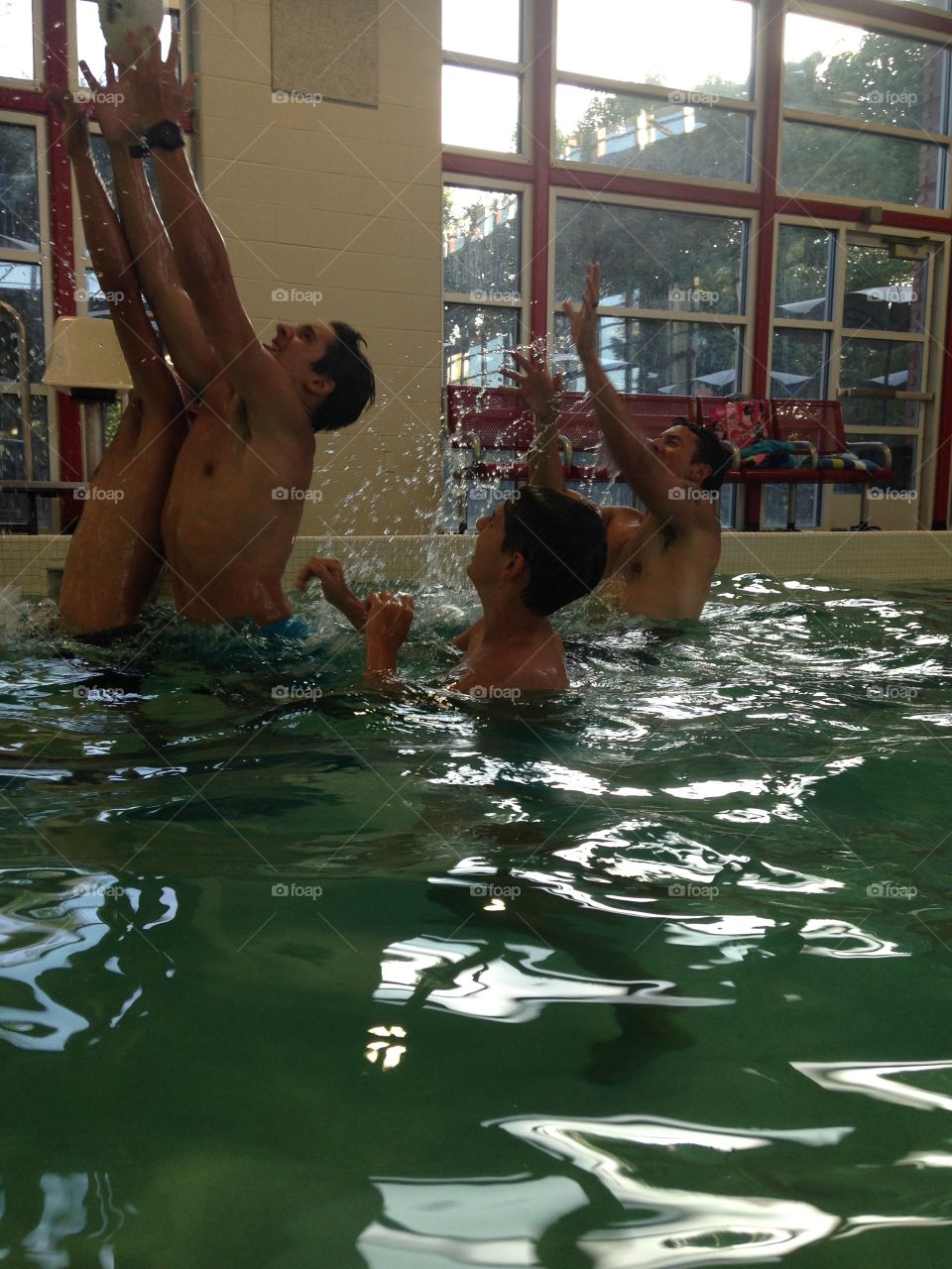 Jump for it. Boys jumping to catch a football in the pool