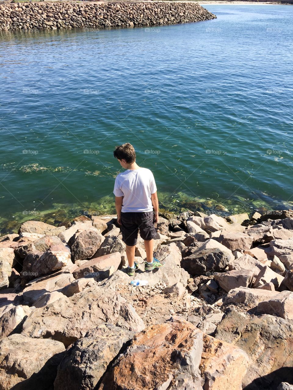  Boy on rocks by ocean 