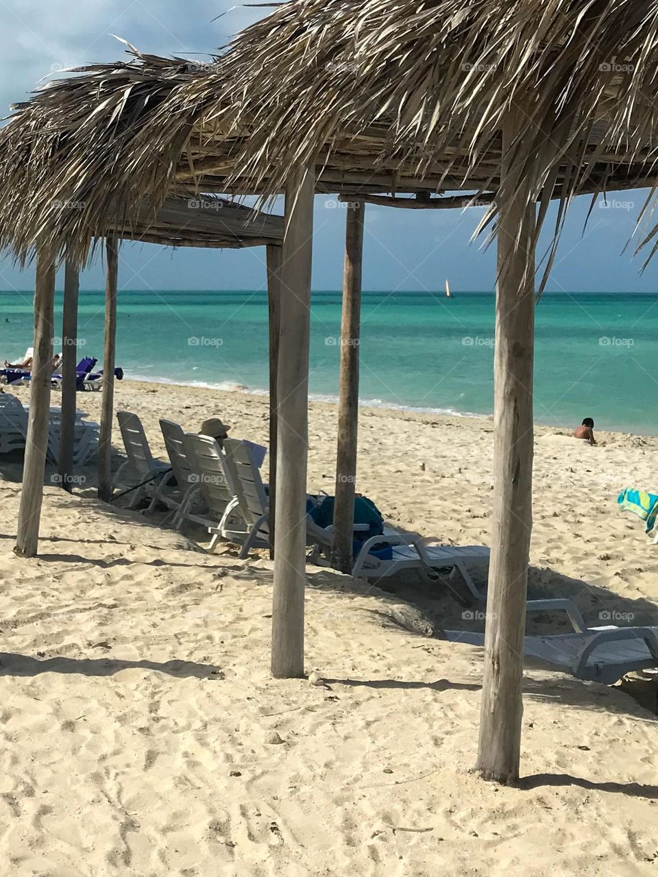 Beautiful view of the turquoise sea with cabanas on the shoreline and loungers underneath
