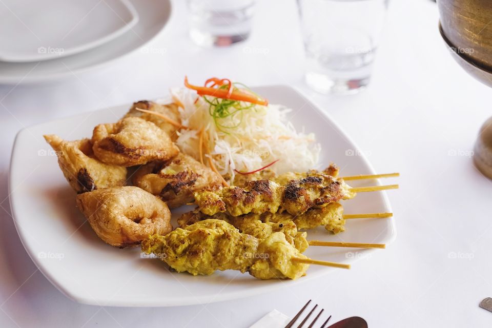 Pork Satay served with curry puffs. Pork satay or chicken satay is Asian gourmet appetizer. Soft focus.