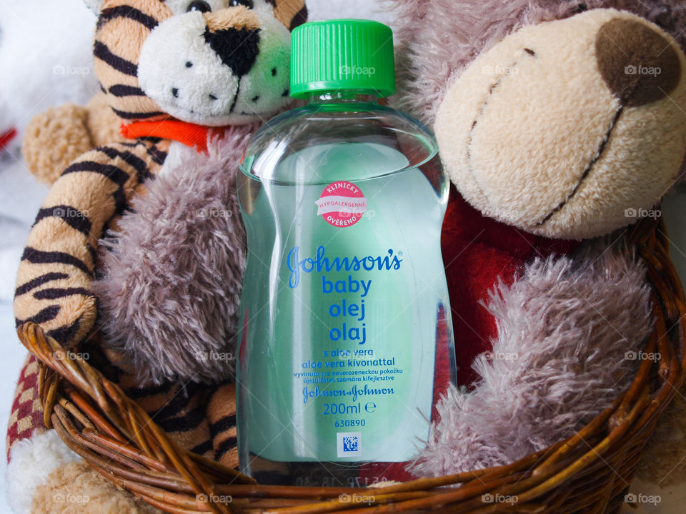 Plush toys in a wooden basket, Johnson's Baby oil in the middle.