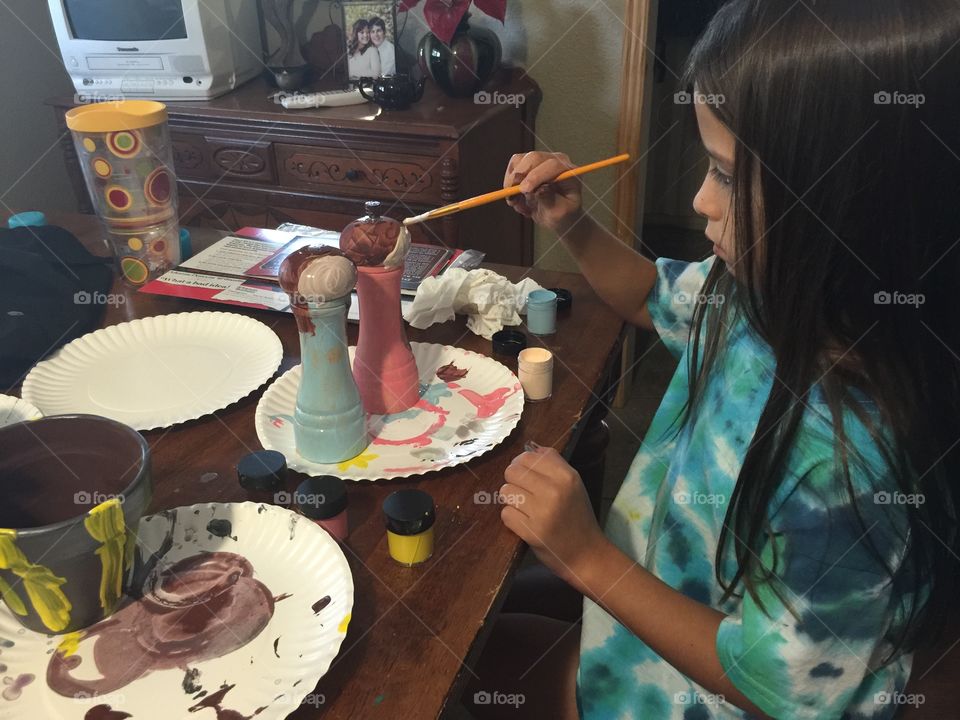 A little girl creating a work of art with paints. 