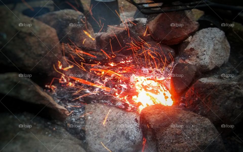 Blowing at the embers at a fire pit, camping