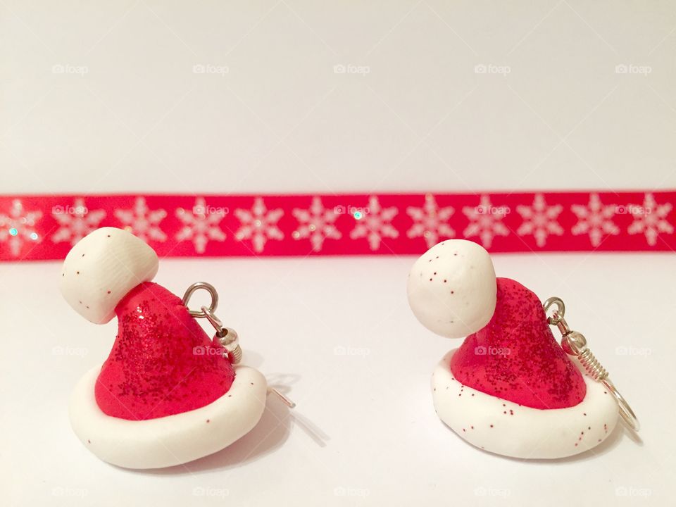 Santa's hat earrings with red ribbon in the background