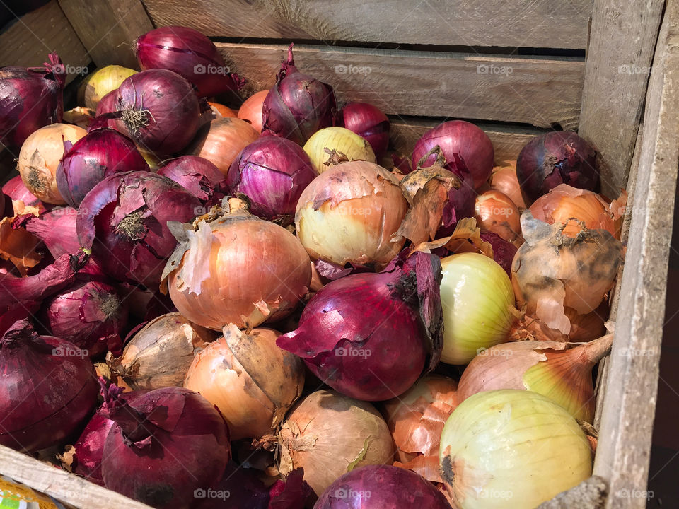 Wooden box with organic cultured mixed food onion for sale at farmers market in fall.