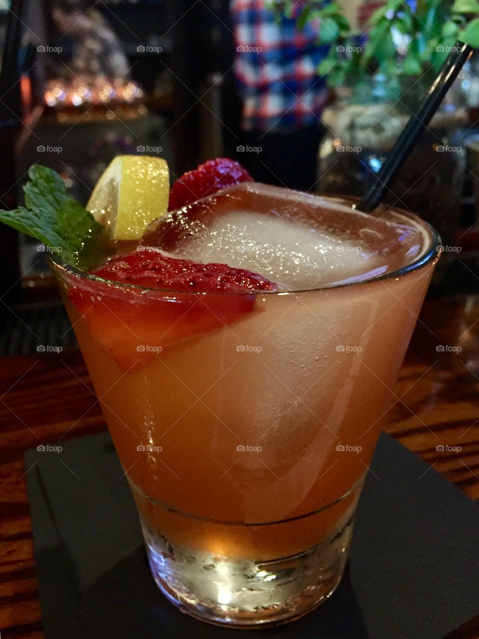 Handcrafted strawberry lemon martini garnished with fresh strawberries lemon and mint leaf.