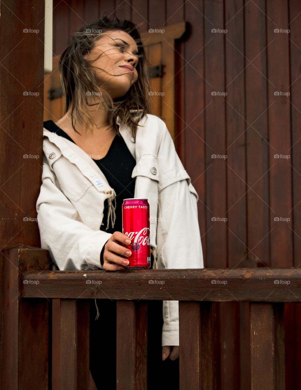 Modeling with coca cola with a woody background and windy weather.