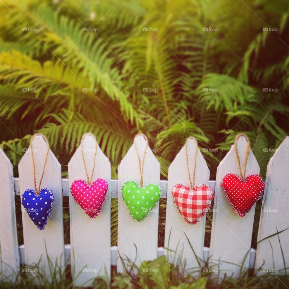 Multi colored hearts hanging on fence