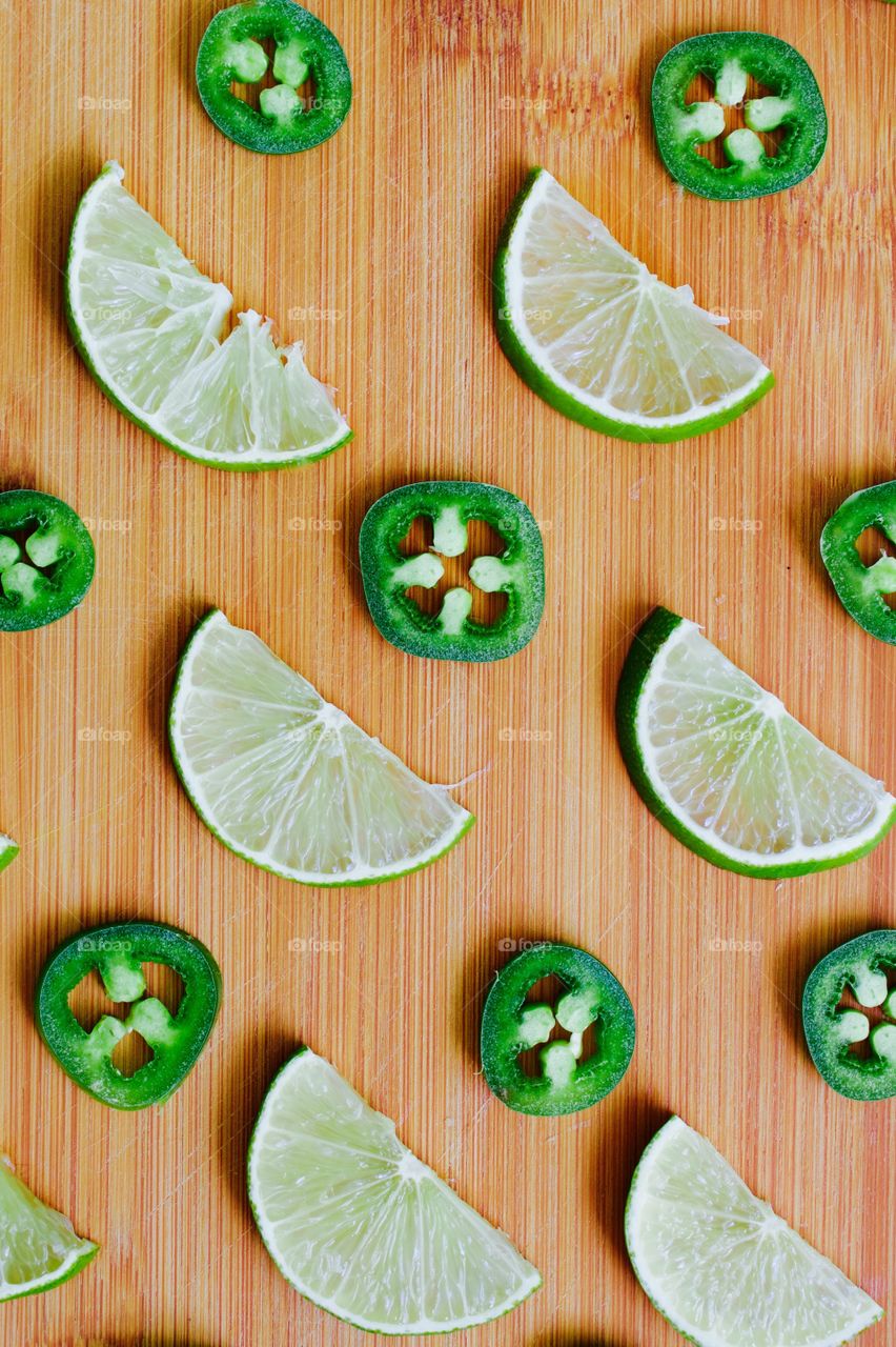 Flat lay of lime and jalapeño slices arranged on a bamboo cutting board