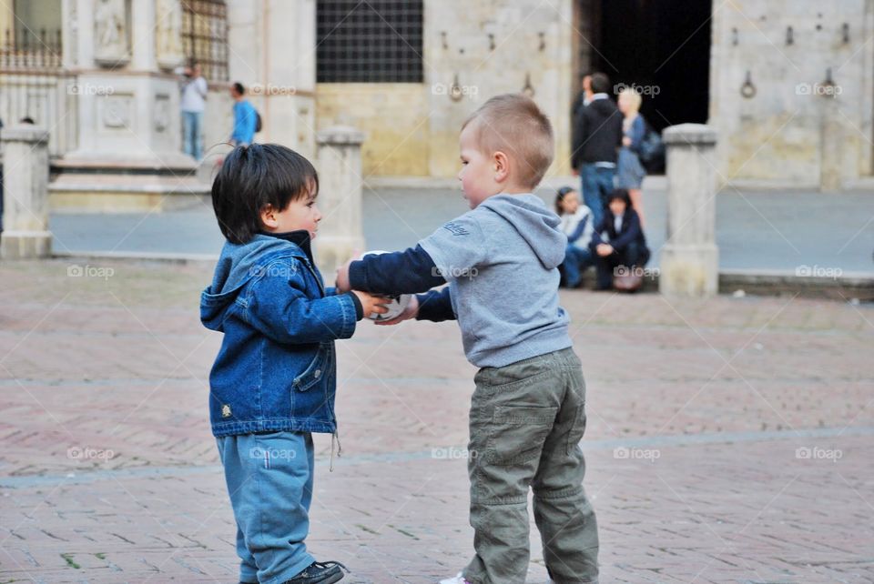 Learning to share. Two little boys learning to share one ball
