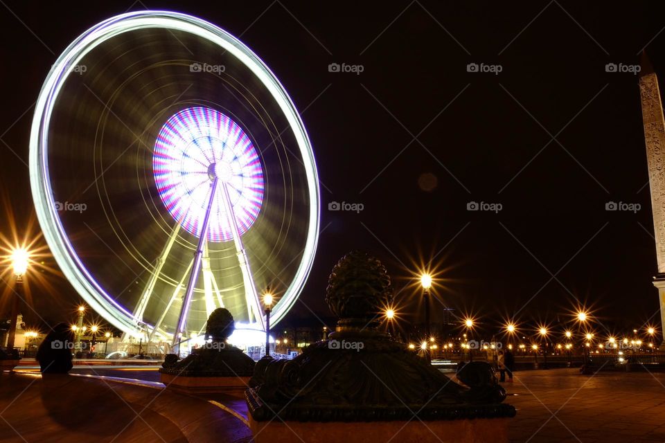 Ferris whee in motion in Paris, French Ferris wheel at night, lights and motion at night, speed of a Ferris wheel in France, blurred motion of a Ferris wheel