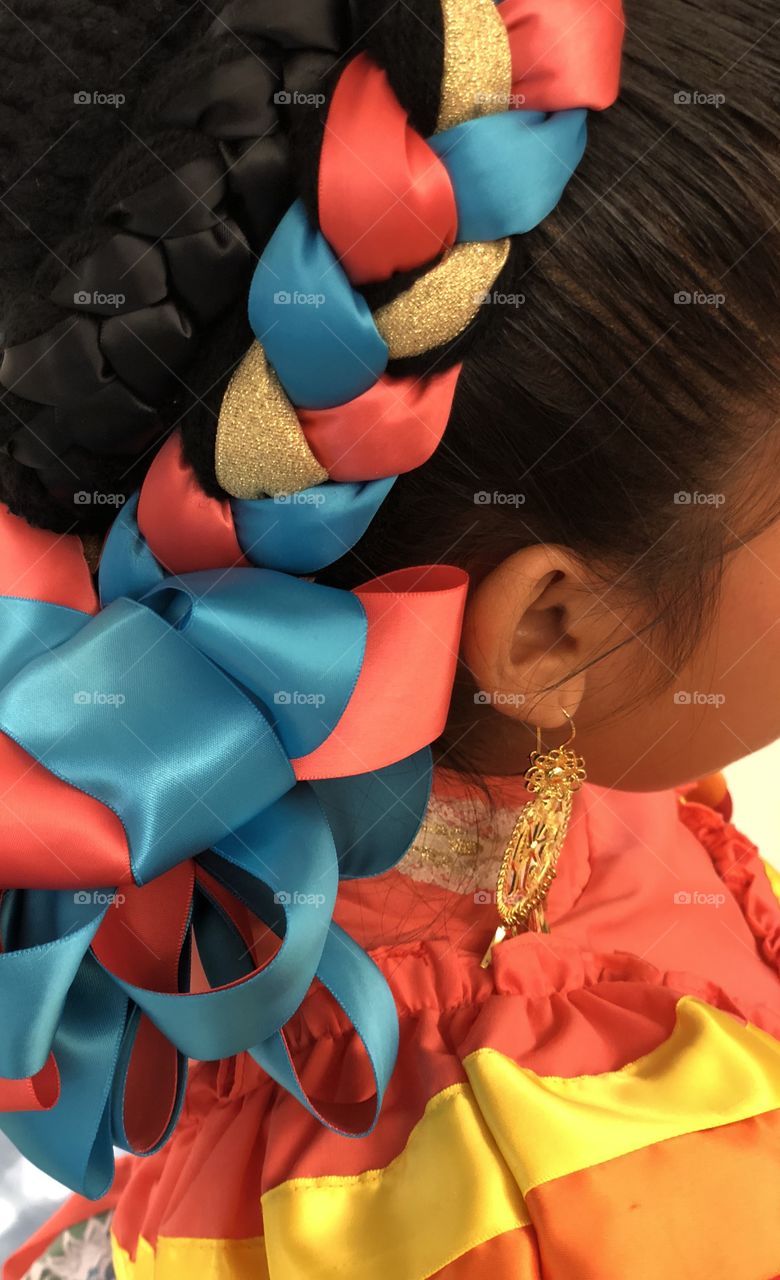 Ballet Folklórico young female girl dancer with colorful ribbon braided into her hair bun and gold earrings 