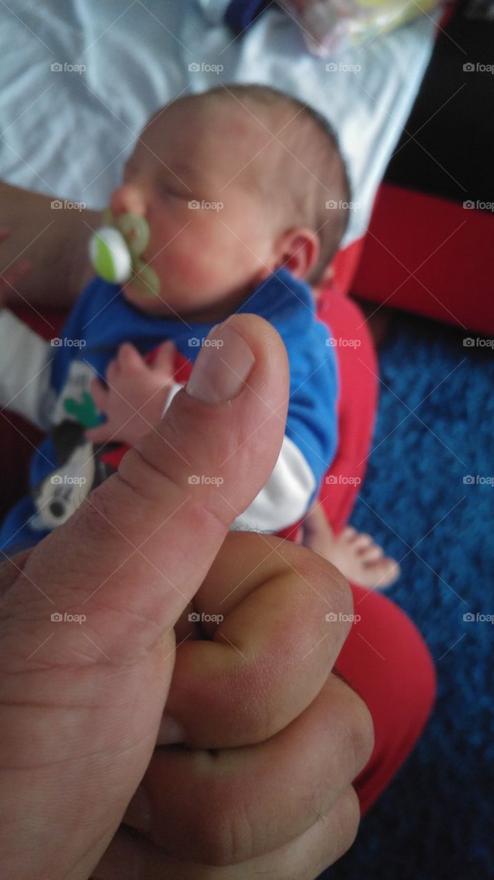 Baby with pacifier sleeping on parent's lap