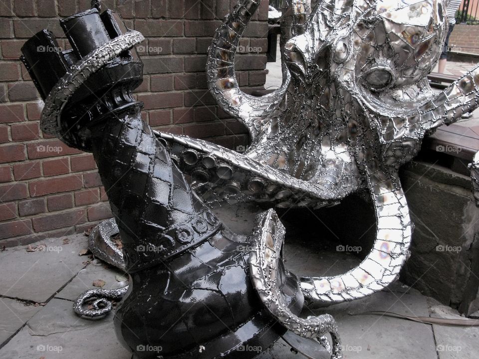 Sculpture of a metal octopus holding a black chess piece, Hastings Old - UK 