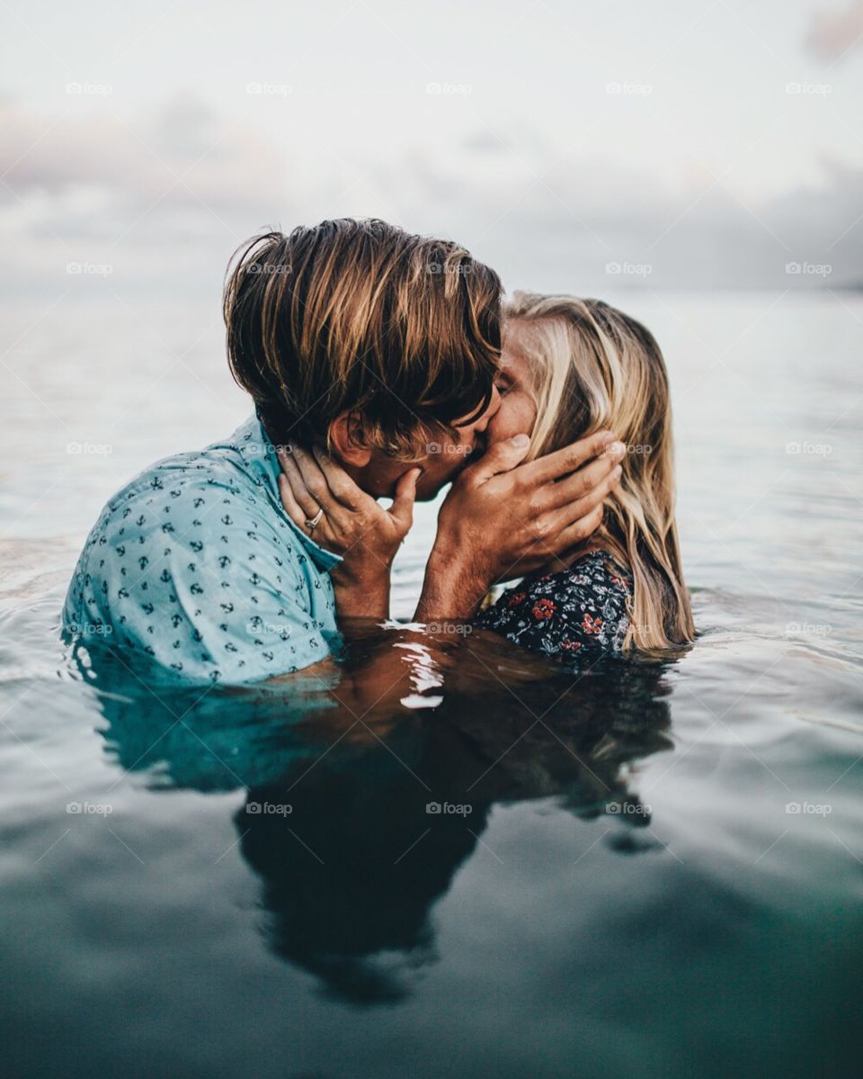 Couple kisses in the ocean in Hawaii.