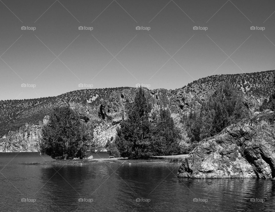 A giant boulder among the juniper trees on the shore at Prineville Reservoir on a sunny summer morning 