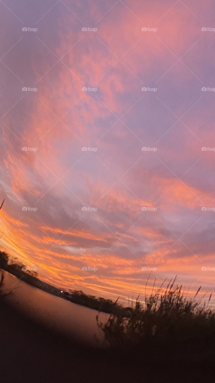 Sundown Completed Sky is opening up. Blistering Orange Slivers along with Yellows upper atmosphere bleeding down to the lower with Grays Blues Violets tops of high clouds getting into the act by opening up.