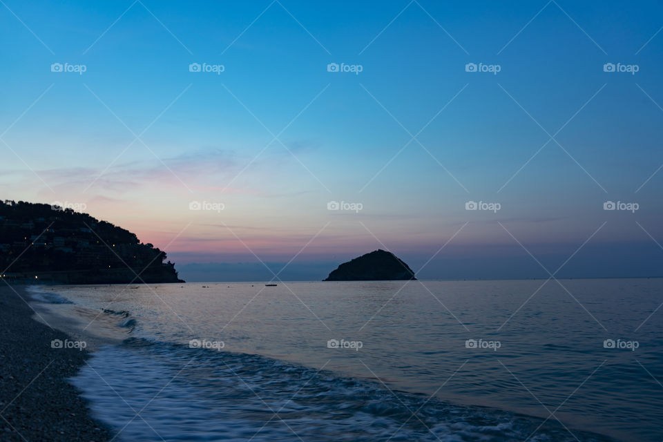 Sunrise over the sea. The sun rises from behind the peninsula and passes from the islet next to it.
Wonderful colors are created, including purple, red, orange, blue.