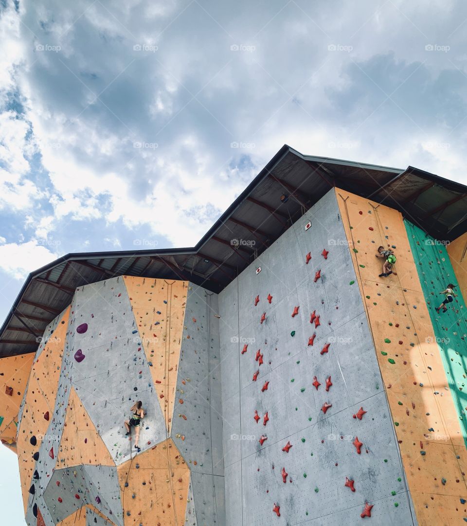 Woman climbing at concrete wall with holds 