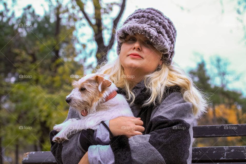 A portrait of a woman with a cap in a gray cape and Jack Russell terrier dog