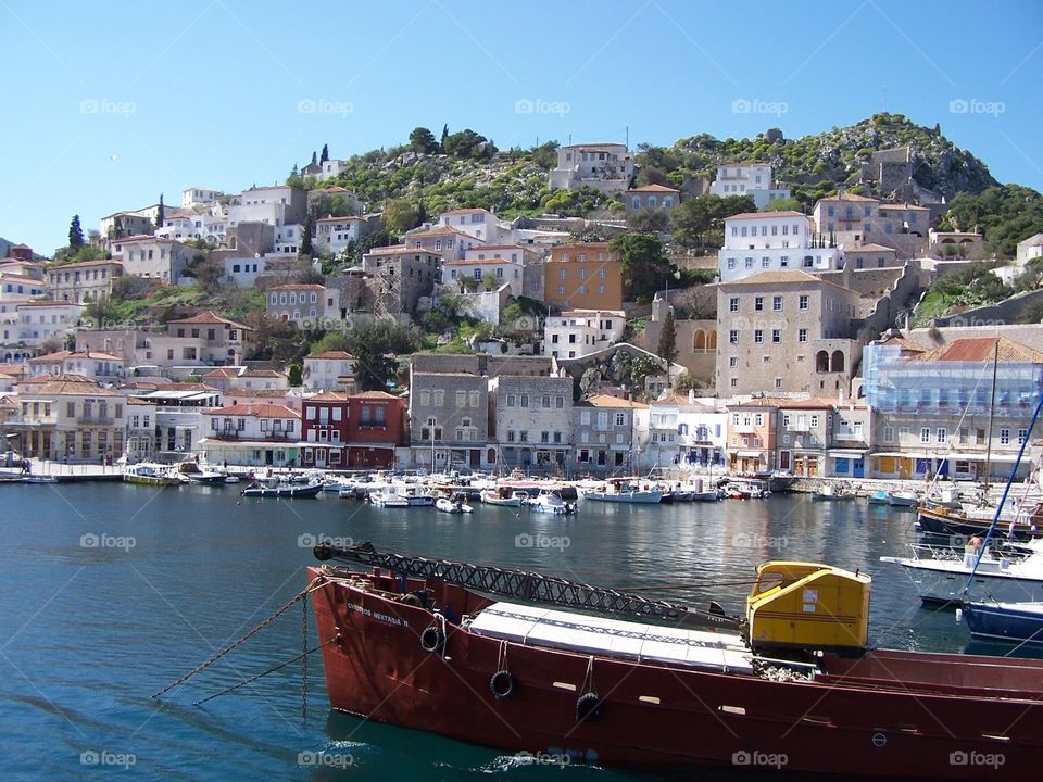 Mahogany boat floating in front of Greek island with village in the Aegean 