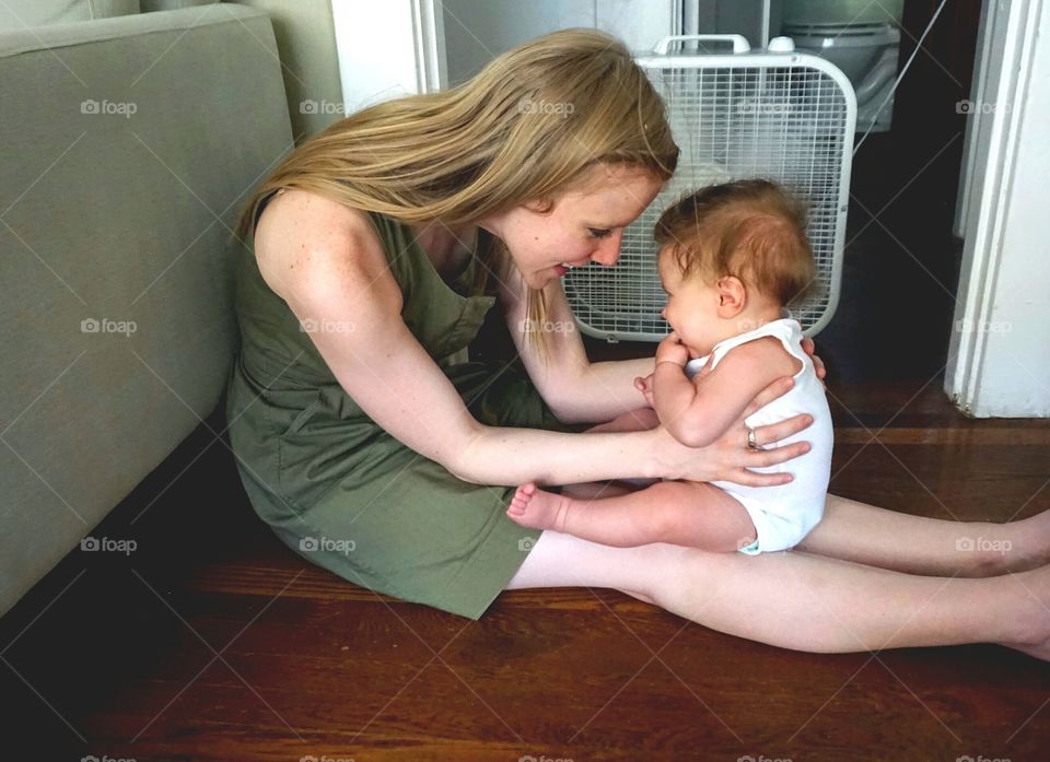 Happy mother and baby sitting on floor in house