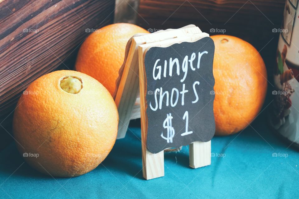 “Ginger Shots” signage surrounded by oranges.