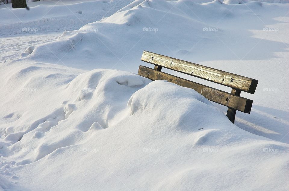 Bench in the park covered with snow