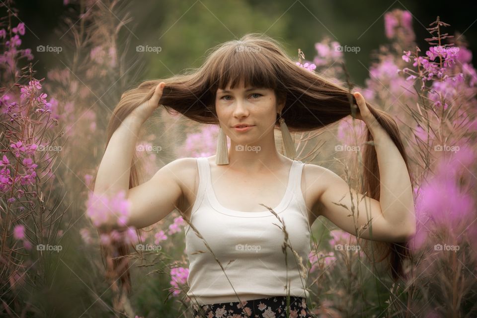 Beautiful young woman in a field of blossom flowers in boho style