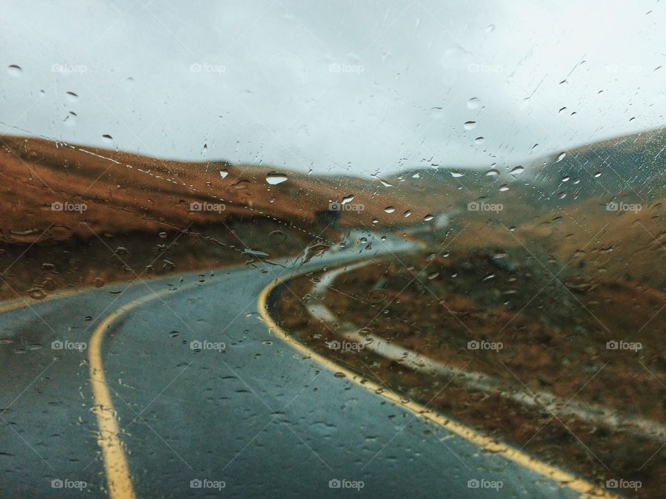 A mountain road view from a car window during a rainy day