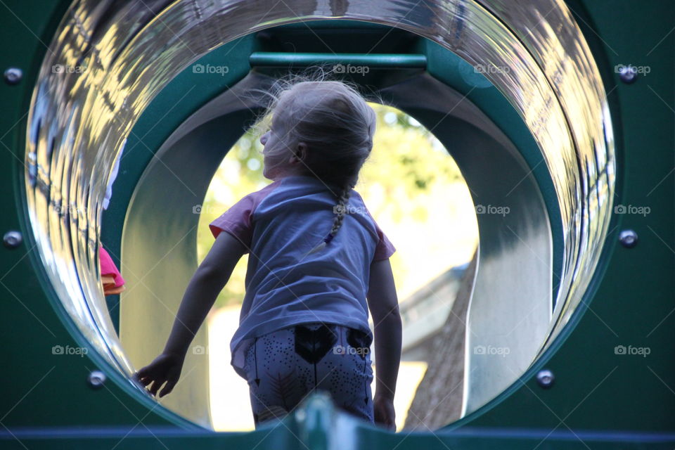 Young Girl in a  playground equipment tunnel