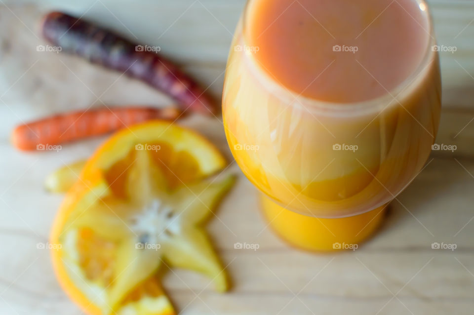 Making fresh home made juice with different colored sweet carrots, orange and tangy carambola star fruit for a vitamin a, vitamin c  nutritious refreshing drink