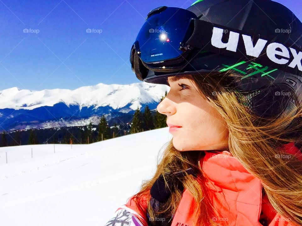 Selfie of woman with ski helmet and ski glasses with mountains in the background