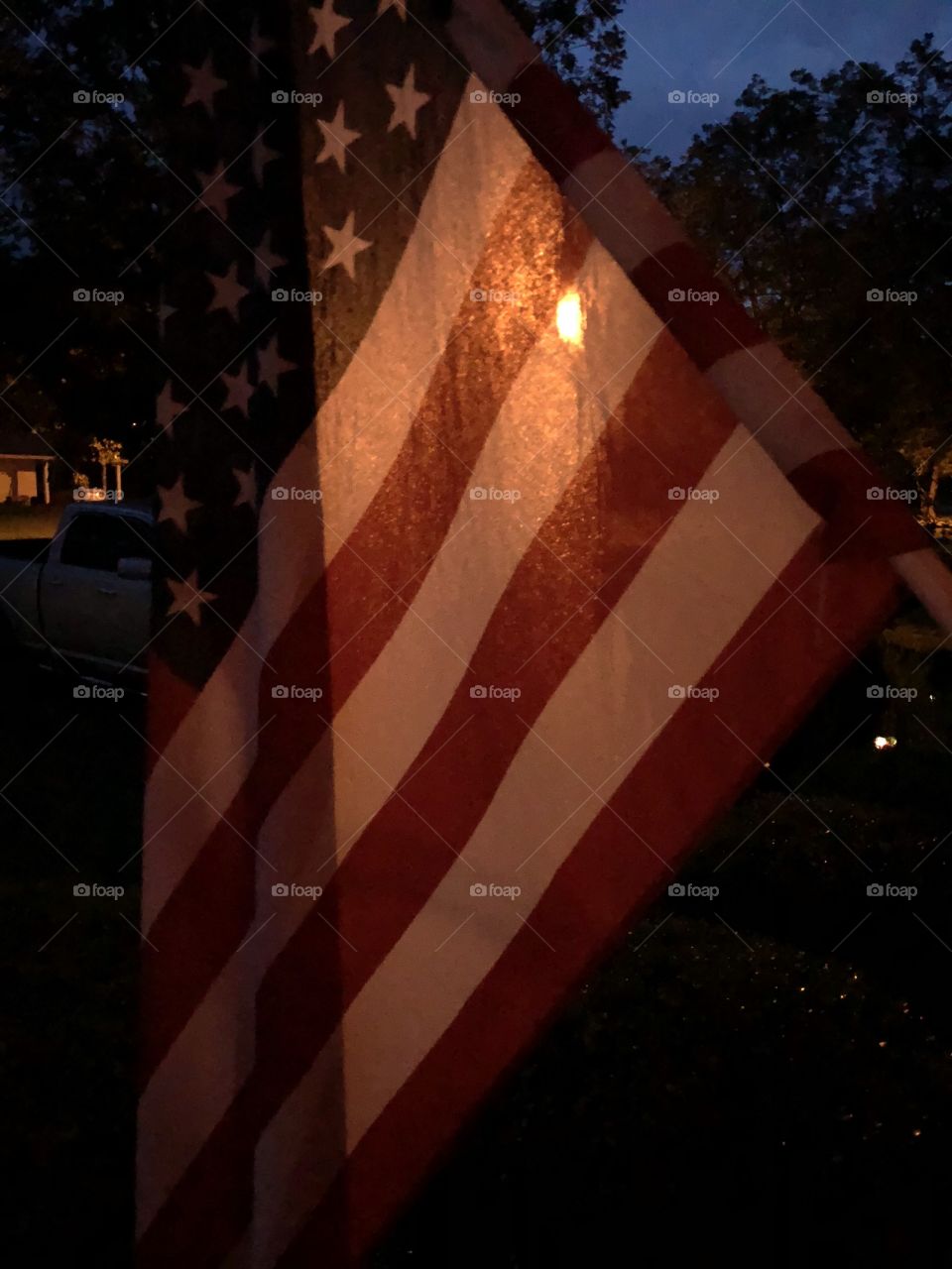 Our American flag at night with street lamp glow shining on it.