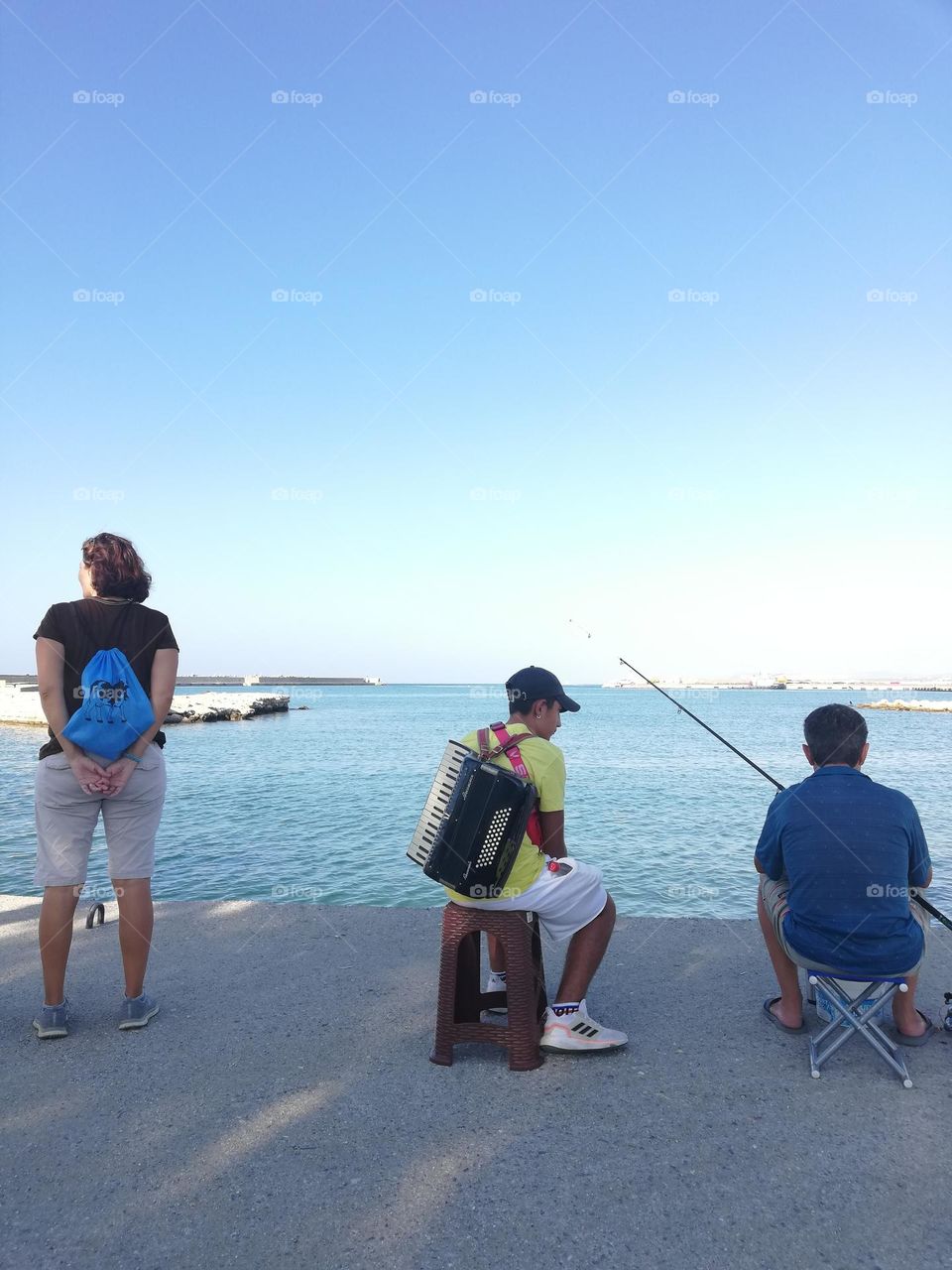 fisherman, musician and tourist looking sea