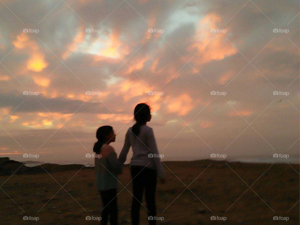 Two girls looking at a wonderful and maguc sunset.