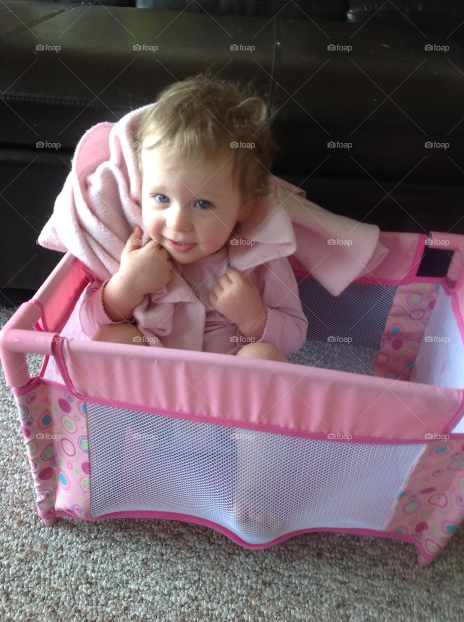 Baby girl playing in doll crib