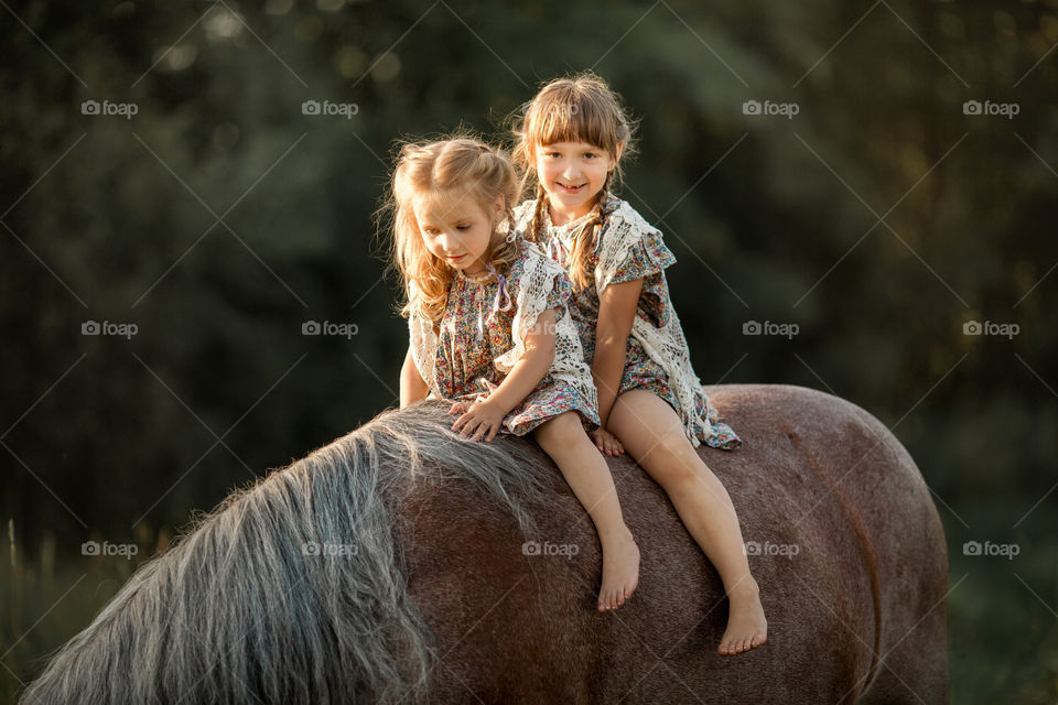 Portrait of little sisters with  horse