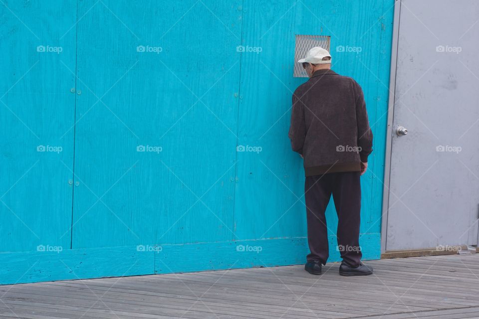 Man looking through small window of house