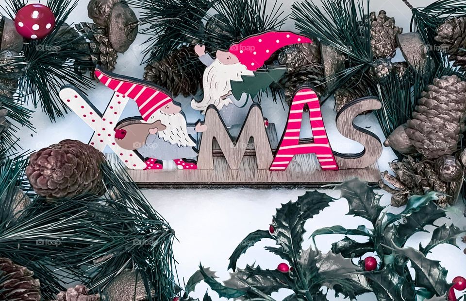 A red & white Xmas sign, surrounded by a festive garland 