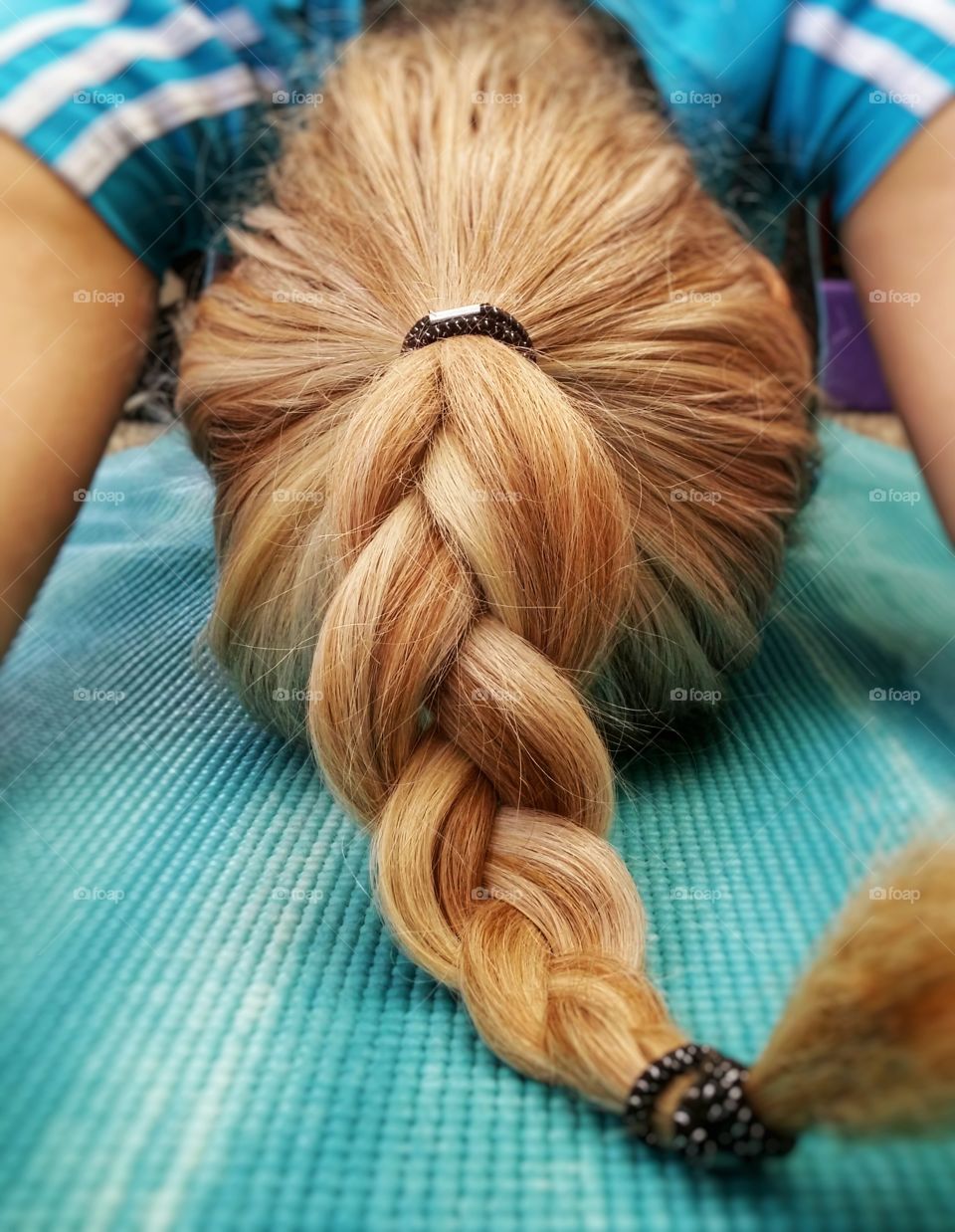 Staying in good shape with yoga child's pose a woman with blond braided hair close up on a mat