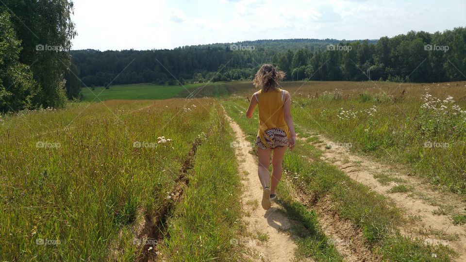 Rear view of a woman walking on path in field