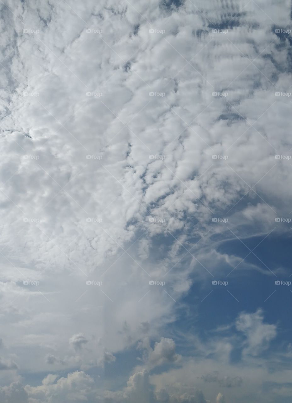 Two different clouds with different image in the blue sky.