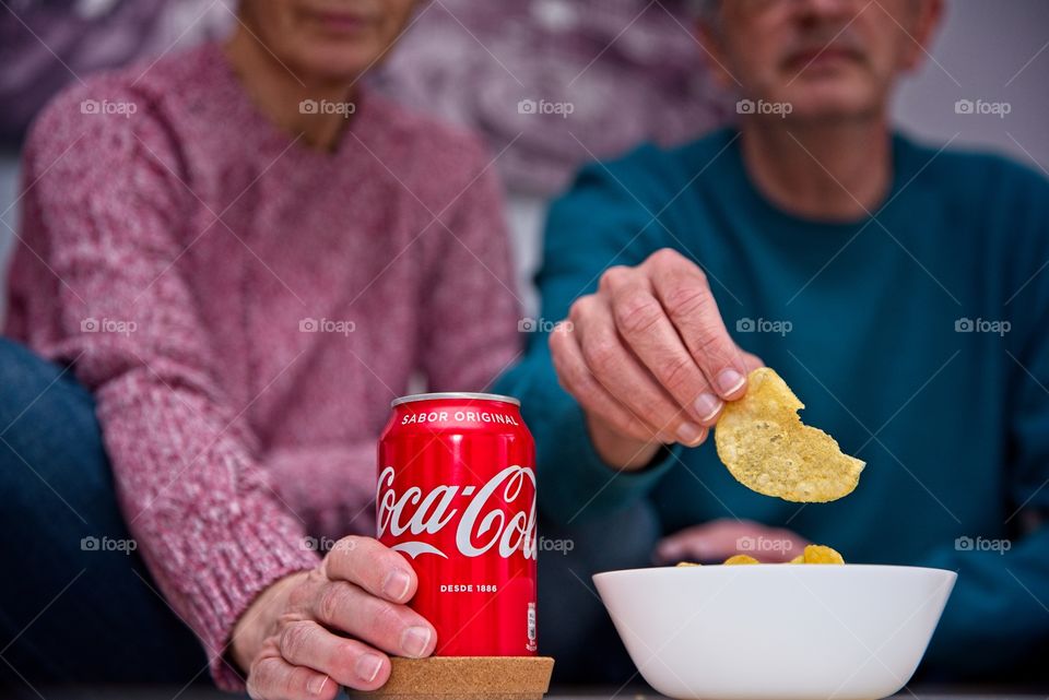 Couple eating a snack with Coca Cola while watching football