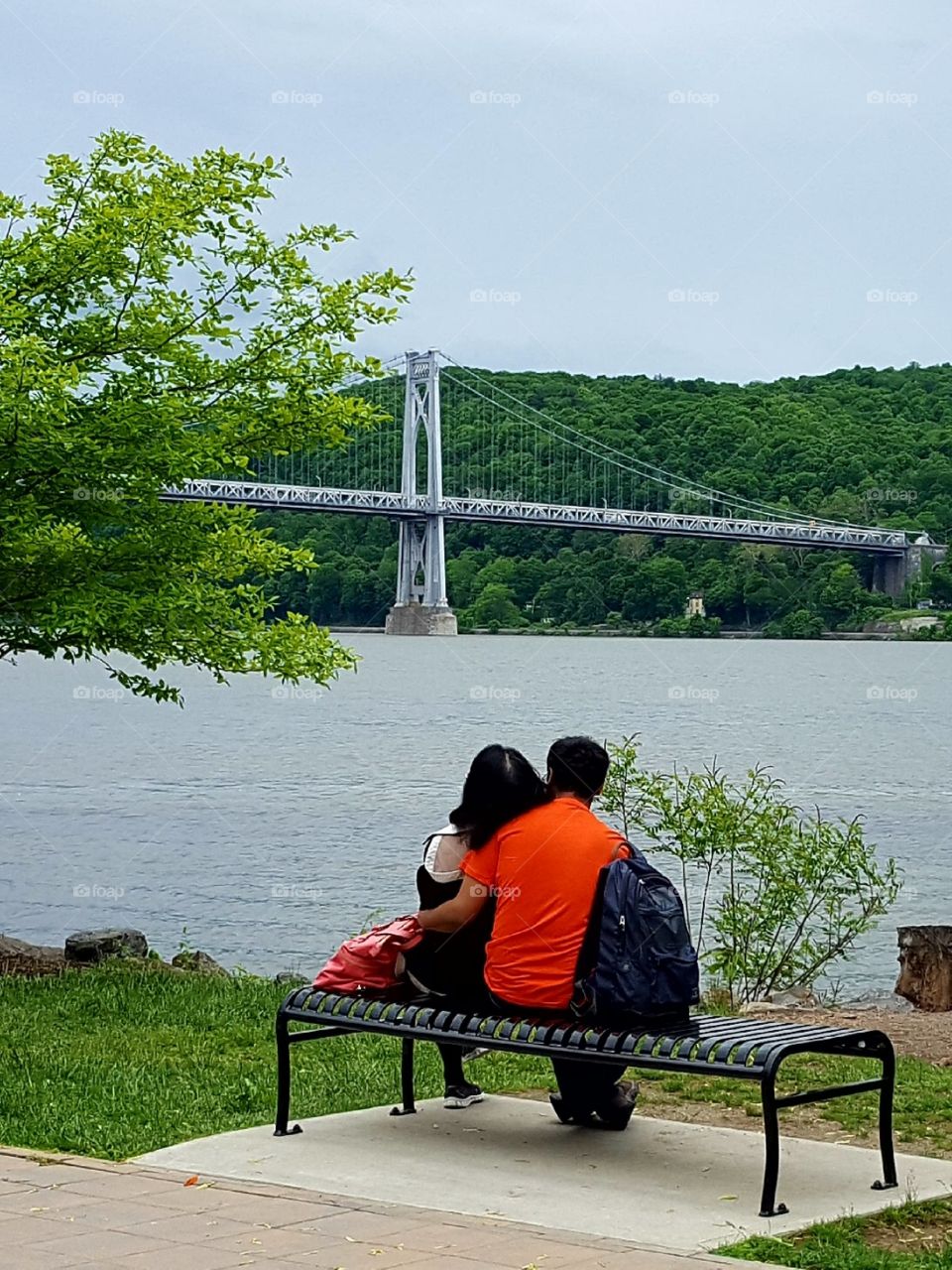 A romantic couple rests and watches the peaceful river flow.