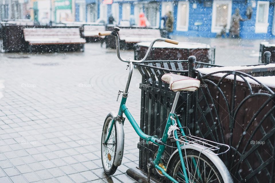 Old fashioned retro bike. City street with first snow, snowfall, selective focus, winter background, textured
