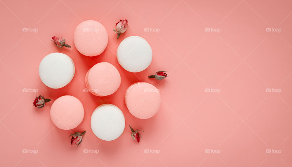 Top view of colourful macarons field with cream on the pastel background. Copy space.