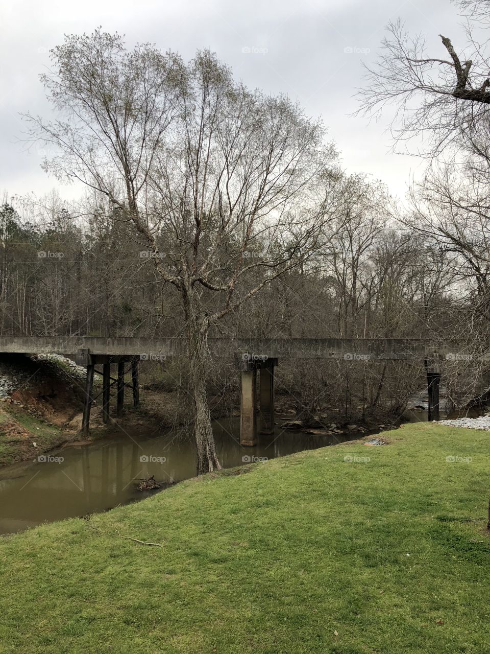 A side view of a country bridge over a creek. 