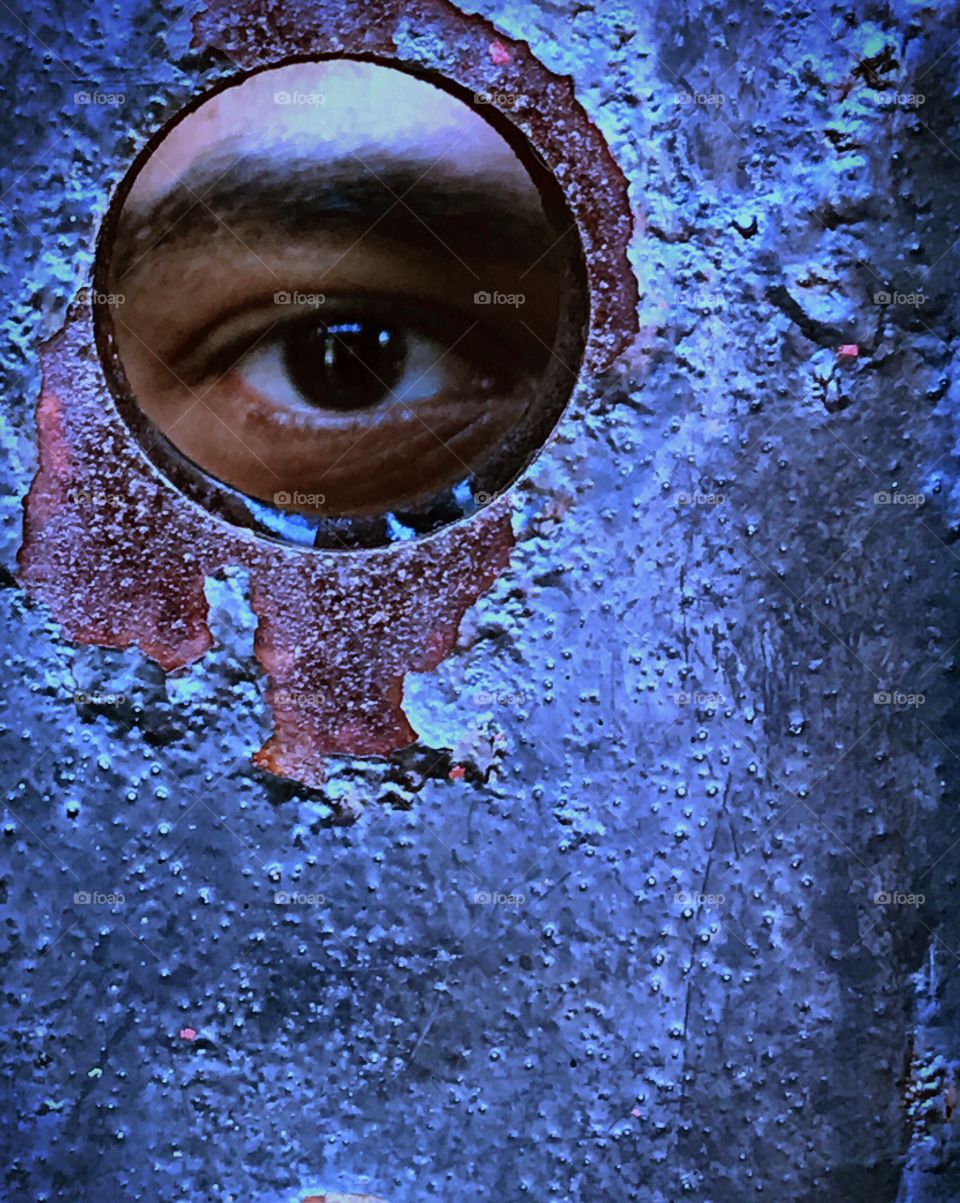 Eye peeping through rusted metal door, New York